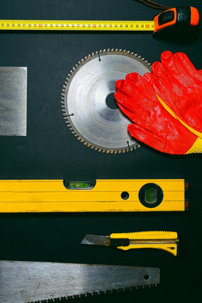 Flat lay of tradesman tools including circular saw, level, gloves and tape measure